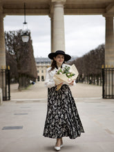 A lady wears a blouse and a skirt.